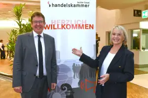 Bundesrat Alber Rösti steht lächelnd neben Elisabeth Schneider-Schneiter, sie zeigt auf ein Willkommensschild