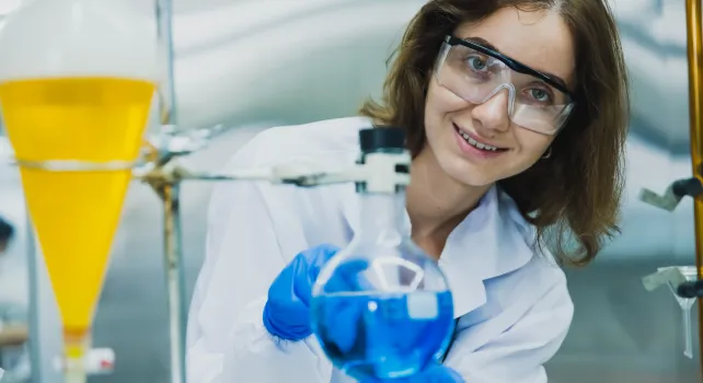 Das Bild zeigt eine junge Frau beim Löten vor technischen Geräten