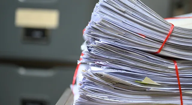 Das Bild zeigt zwei grosse Bündel Papier auf einem Schreibtisch