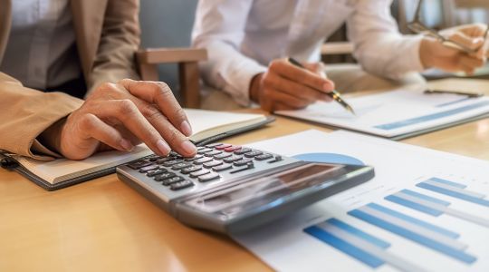 Zwei Personen im Büro mit Dokumenten und Taschenrechner