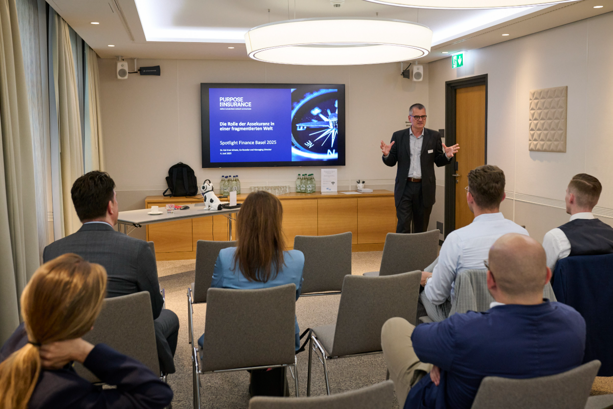 Referent vor einem Bildschirm, ihm zugewandt sechs Zuhörende