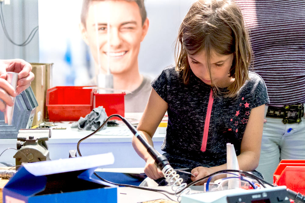 Kleines Mädchen hält einen Lötkolben in der Hand