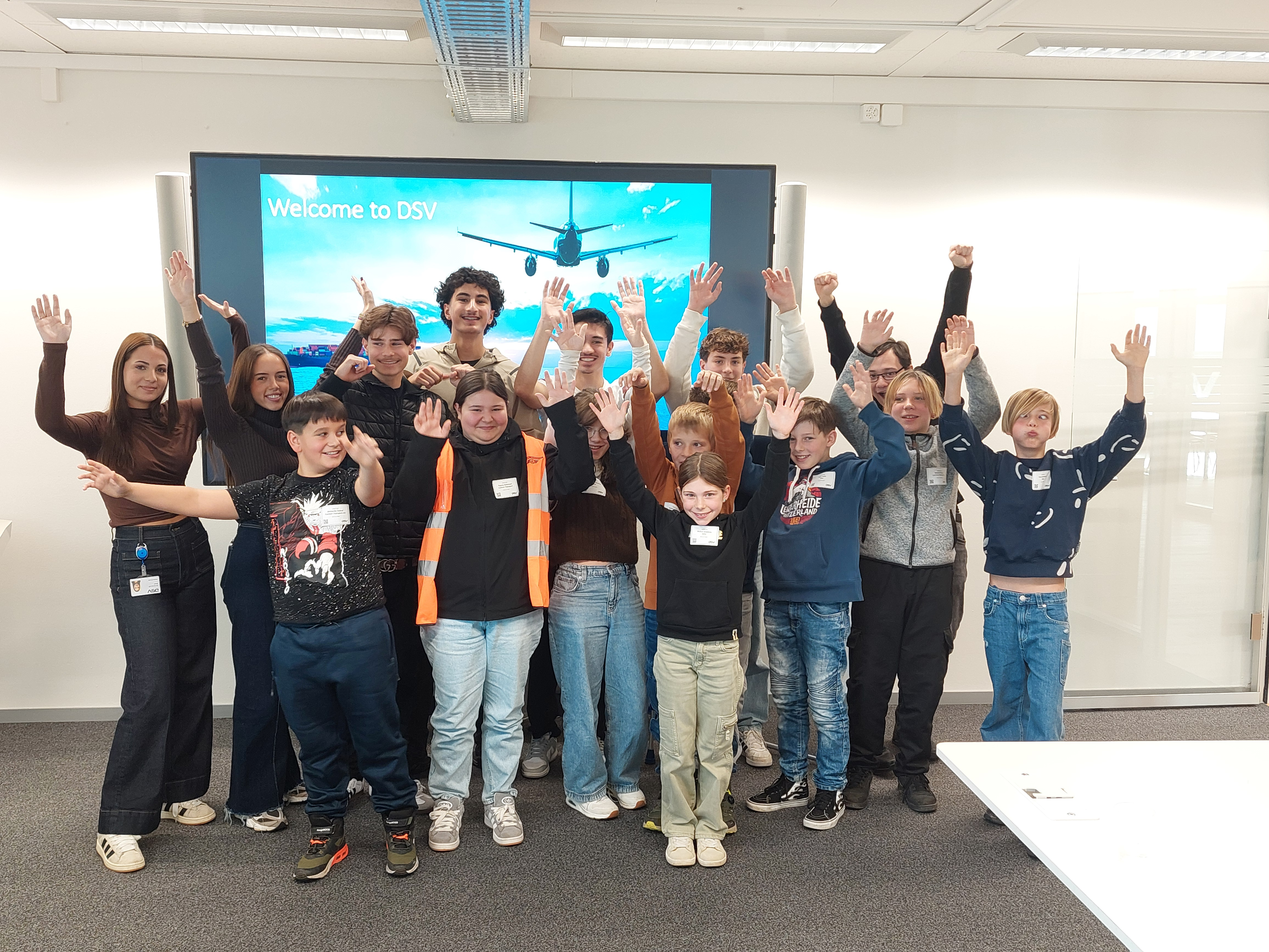 Bild zeigt ein Gruppenfoto von Schülerinnen und Schülern, die ihre Hände nach oben strecken.