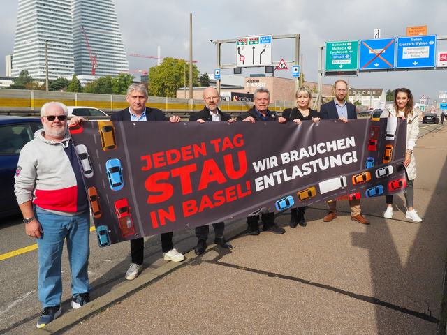 Foto der Petenten auf der Schwarzwaldbrücke (v.l.) Markus Haas, NQV Breite-Lehenmatt;  Daniel Seiler, ACS beider Basel; Lukas Ott, TCS beider Basel; Hans-Peter Ebneter, NQV Oberes  Kleinbasel; Tamara Hunziker, Gewerbeverband Basel-Stadt; Silvan Buchecker, Handelskammer beider  Basel; Birgit Kron, TCS beider Basel.  